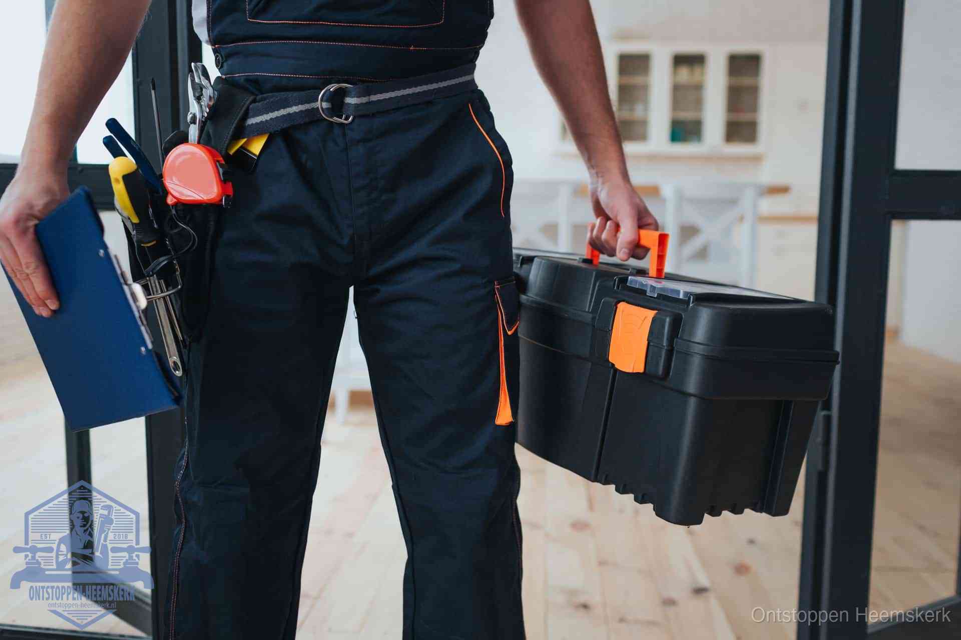 Een monteur met gereedschapsriem en klembord in een keuken, klaar om een transparante prijs voor het gootsteen ontstoppen in Heemskerk te geven