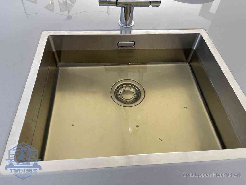 Stilstaand water in een rvs spoelbak dat niet wegloopt, een duidelijk signaal van een gootsteenverstopping in Heemskerk
