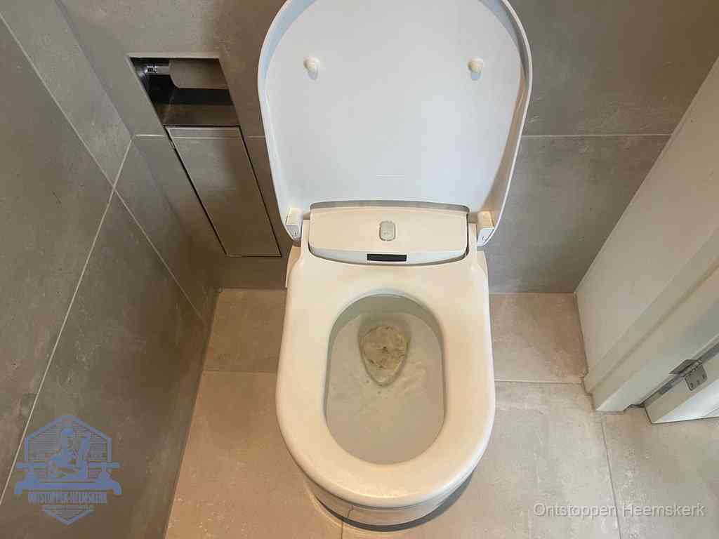 Een wit hangtoilet waarin een prop wc-papier op het water blijft drijven, een duidelijk signaal van een verstopte wc in Heemskerk