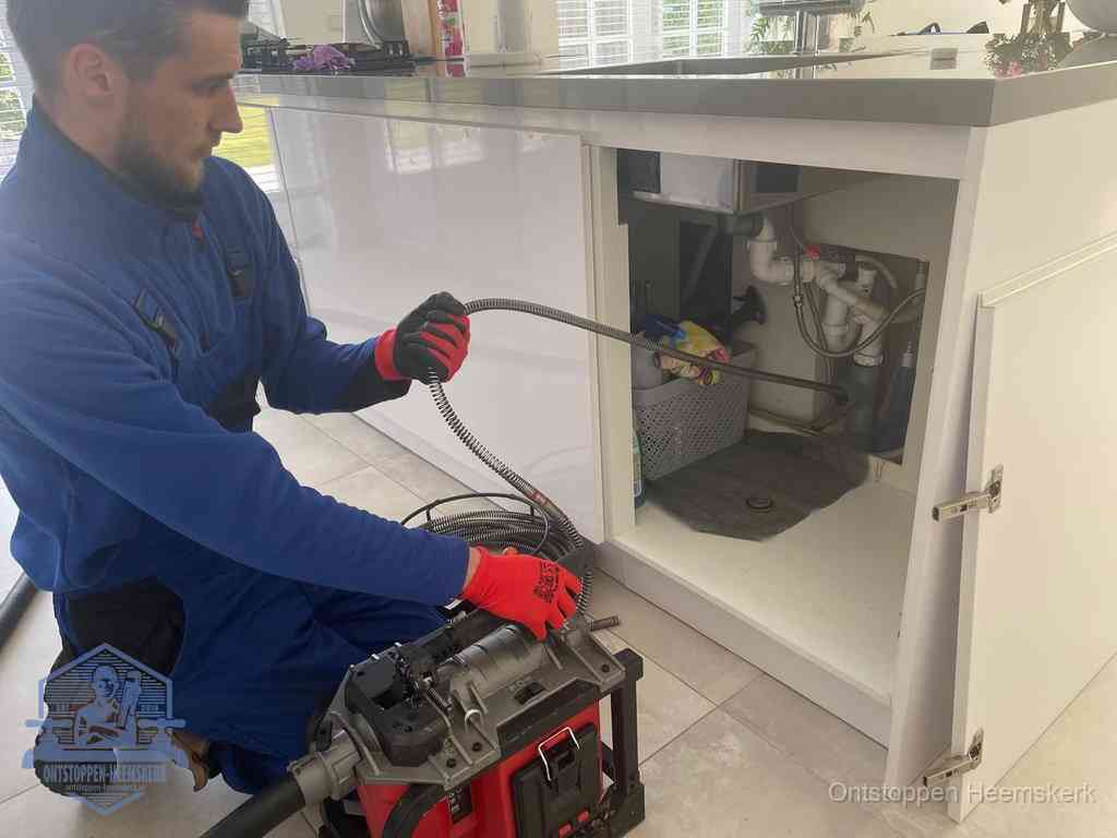 Een monteur reinigt de keukenafvoer grondig met een veermachine om terugkerende gootsteenverstoppingen te voorkomen in Heemskerk