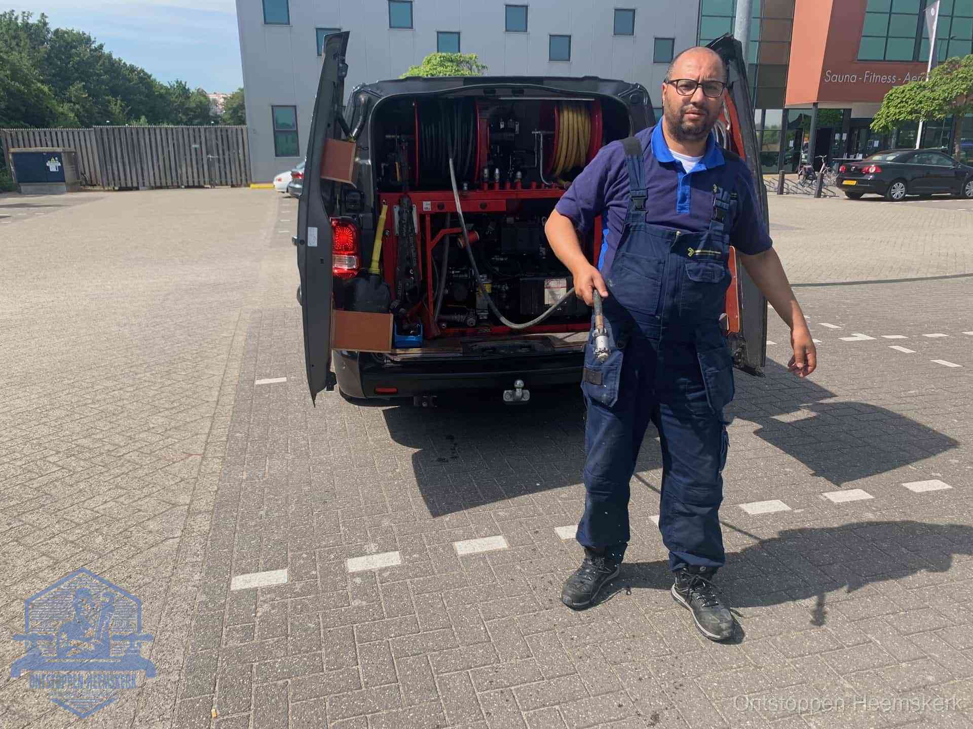 Een monteur bij zijn bestelbus met een hogedruk- en rioolreinigingsunit, klaar om de oorzaak van terugkerende wc-verstoppingen aan te pakken in Heemskerk