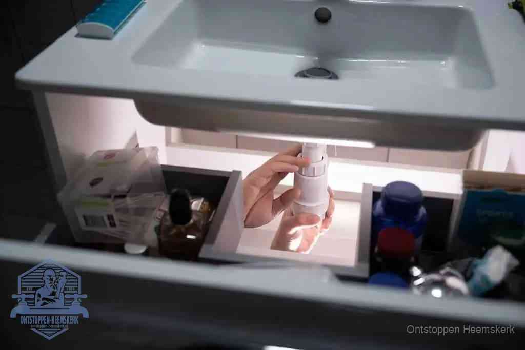 Een pompfles met zeep boven een wastafel in de toiletruimte, de warm water en afwasmiddel-methode om de wc te ontstoppen in Heemskerk