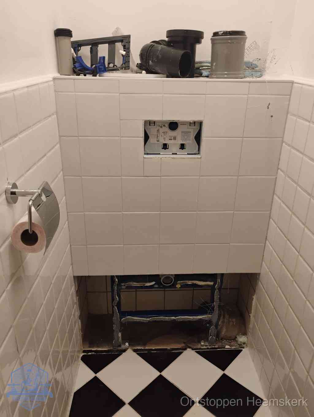 Een toiletruimte waar het hangtoilet en de inbouwreservoir-onderdelen zijn vrijgelegd voor onderhoud, periodiek nazicht voorkomt een wc-verstopping in Heemskerk